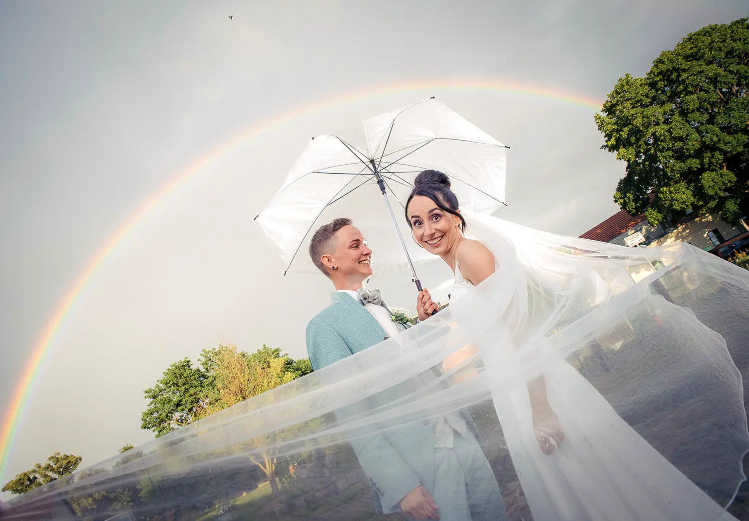 Queeres Hochzeitspaar unterm Regenbogen – Zeit für eine Regenbogenhochzeit